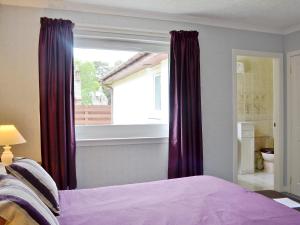 a bedroom with purple curtains and a window at Tall Pines in Carrbridge