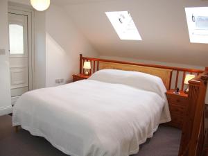 a bedroom with a white bed and a window at Woodstore Cottage in Lazonby