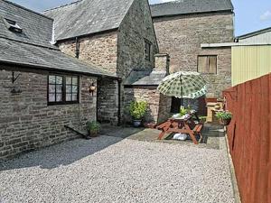 a patio with a wooden table and an umbrella at The Old Farmhouse in Blakeney