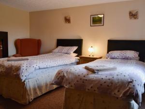1 dormitorio con 2 camas y mesa con lámpara en The Old Farmhouse, en Blakeney