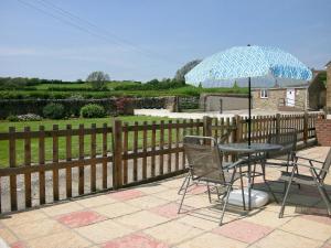 a table and chairs with an umbrella on a patio at Woodpecker in Burton Bradstock