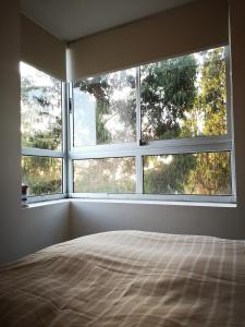 a bedroom with two large windows and a bed at Espectacular departamento amoblado en Algarrobo Norte in San Antonio
