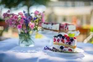 a cake with berries on a table with a vase of flowers at Hotel Waldhaus Föckinghausen in Bestwig