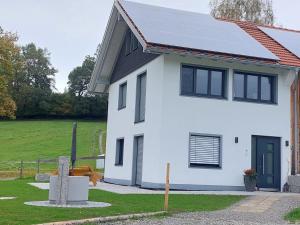 a white house with solar panels on the roof at Ferienhaus Rasch in Maierhöfen