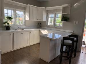 a kitchen with white cabinets and a sink and a counter at Trincity Apartment in Trincity 