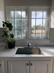 a kitchen with a sink and two windows at Trincity Apartment in Trincity 