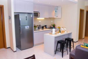a kitchen with a refrigerator and a counter with stools at GTC 1Br Apartment on Westlands Road -with Gym& Pool in Nairobi