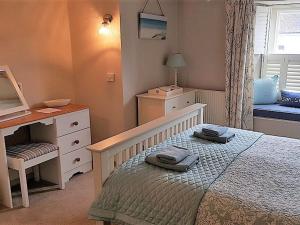 a small bedroom with a bed and a desk and a window at Below Deck in Fowey