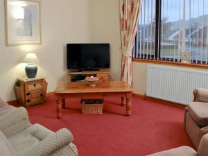 a living room with a tv and a coffee table at Glenloch Cottage in Drumnadrochit
