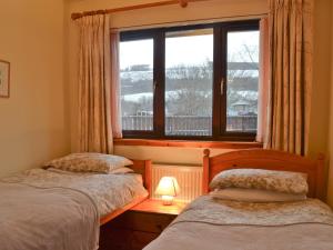 two beds in a room with a window at Glenloch Cottage in Drumnadrochit