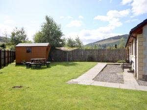 a backyard with a picnic table and a fence at Glenloch Cottage in Drumnadrochit