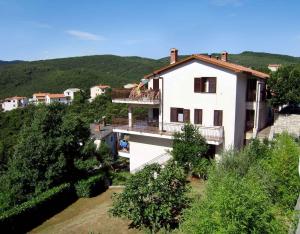a large white house with a balcony and trees at Apartment Rabac 23 in Rabac