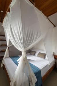 um quarto com uma cama de dossel com lençóis e almofadas brancos em Muita Paz Rooms em Atins