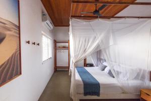 a bedroom with a bed with a canopy at Muita Paz Rooms in Atins
