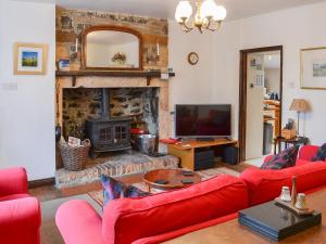 ein Wohnzimmer mit einem roten Sofa und einem Kamin in der Unterkunft Botany Cottage in Chathill