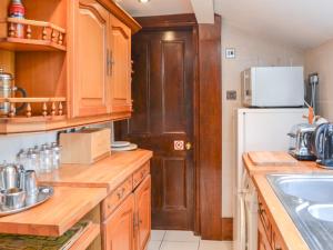 eine Küche mit Holzschränken und einem weißen Kühlschrank in der Unterkunft Botany Cottage in Chathill