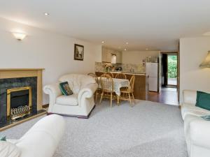 a living room with white furniture and a fireplace at Coot Cottage in Dilham
