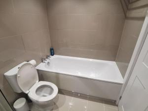 a white bathroom with a toilet and a bath tub at Griffin Apartments in Nottage