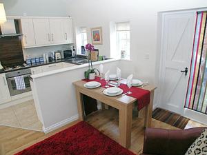 a kitchen with a table with plates and wine glasses on it at The Dairy in Cromer