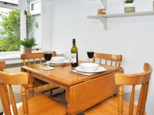 a dining room table with a bottle of wine on it at Osprey Cottage in Bassenthwaite