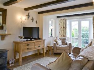 a living room with a couch and a flat screen tv at Starboard Cottage in Winterton-on-Sea