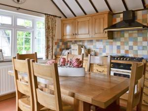 ウィンタートン・オン・シーにあるStarboard Cottageのキッチン(木製テーブル、椅子、コンロ付)