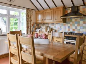 a kitchen with a wooden table with chairs and a stove at Starboard Cottage in Winterton-on-Sea