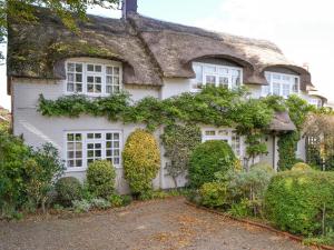a house with a thatched roof with bushes at Starboard Cottage in Winterton-on-Sea