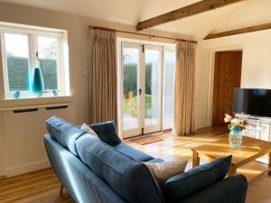 a living room with a blue couch and a table at The Stables in Occold