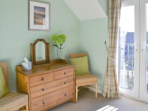 a room with a dresser and two chairs and a mirror at Aidan Cottage in Craster