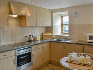 a kitchen with wooden cabinets and a sink and a table at Apple Tree Cottage -18512 in Kilkhampton