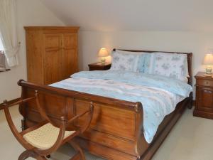 1 dormitorio con 1 cama con marco de madera y silla en Apple Tree Cottage -18512, en Kilkhampton