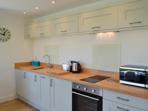a kitchen with white cabinets and a sink and a microwave at Bosuns in Port Isaac