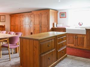 a kitchen with wooden cabinets and a sink and a table at The Barn in Waberthwaite