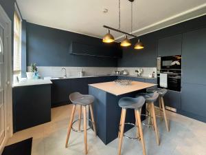 a kitchen with blue cabinets and a island with bar stools at The Cottage At Stanley Villa in Southport