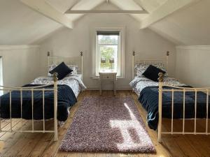 two beds in a room with a window and a rug at The Cottage At Stanley Villa in Southport