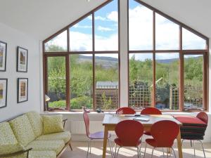 un soggiorno con tavolo, sedie e una grande finestra di 3 Barf Cottages a Portinscale