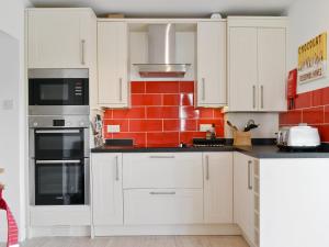 una cucina con armadietti bianchi e un muro di mattoni rossi di 3 Barf Cottages a Portinscale