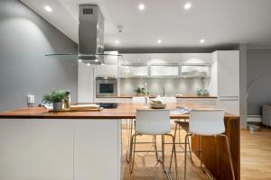 a kitchen with a wooden counter and white cabinets at Fløyen Lux Apartment in Bergen