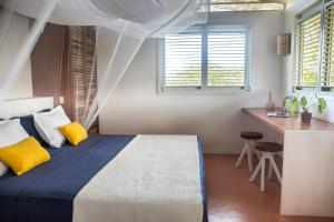 Schlafzimmer mit einem Bett, einem Schreibtisch und Fenstern in der Unterkunft Casa Mais Amor in Atins
