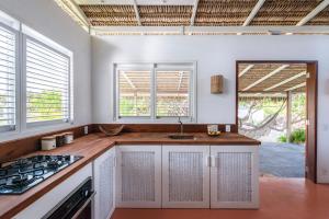 eine Küche mit weißen Schränken, einem Waschbecken und Fenstern in der Unterkunft Casa Mais Amor in Atins
