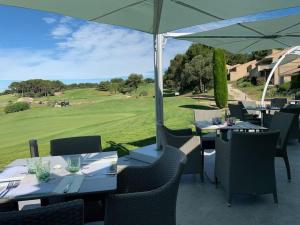 d'une terrasse avec des tables et des chaises offrant une vue sur un parcours de golf. dans l'établissement Escale détente - Résidence 4* au sein d'un Golf, à Saumane-de-Vaucluse