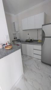 cocina con armarios blancos y nevera de acero inoxidable en Paris Tower Apart 81 Departamentos en Resistencia