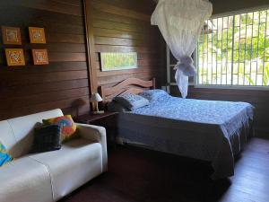 een slaapkamer met een bed, een bank en een raam bij Casa Tapirapé - Barra Grande/BA in Barra Grande