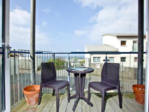 dwa krzesła i stół na balkonie w obiekcie Apartment 7, Ocean 1 w mieście Crantock