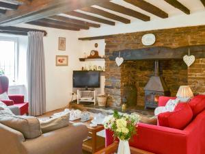 a living room with red furniture and a stone fireplace at West Hurscott Cottage in Swimbridge