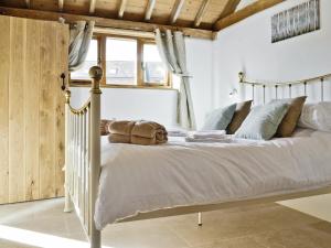 1 dormitorio con 1 cama con sábanas y almohadas blancas en The Cow Shed, en Arlingham