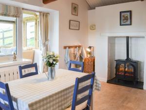 a dining room with a table and a fire place at West Hurscott Cottage in Swimbridge