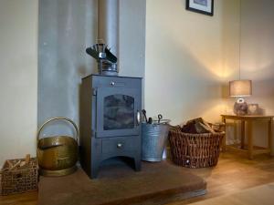 an old wood stove in a room with baskets at Pleacairn Cottage in Dalton