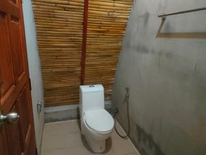 a bathroom with a toilet with a wooden wall at Baanmaiphai Resort in Ban Mo Nae